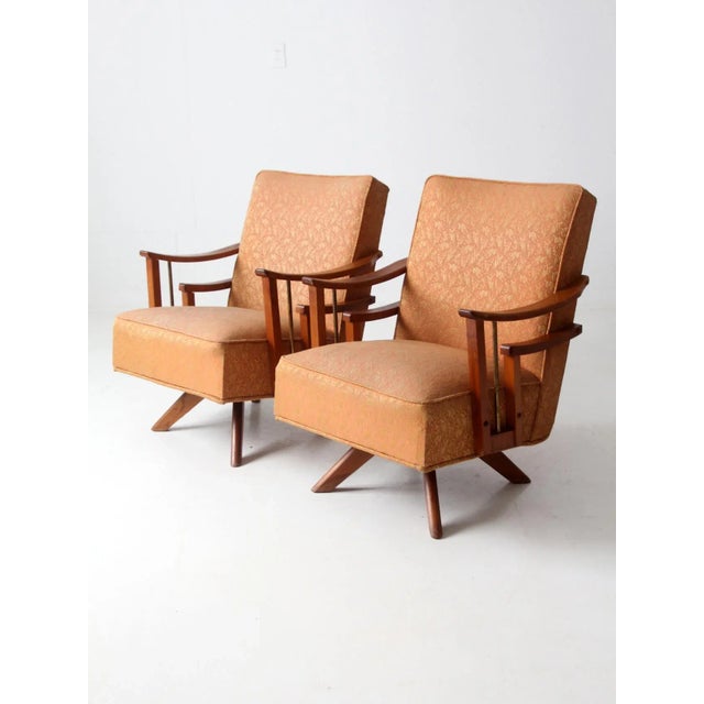 This pair of vintage swivel lounge chairs are ideal for adding a touch of mid-century style to any space. With their warm,...