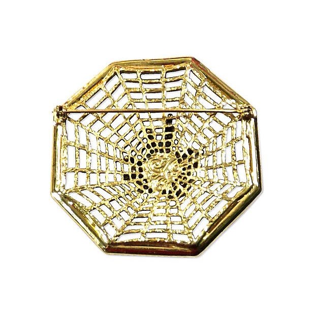 A vintage 1910-1950 gold and crystal spider and web brooch. The brooch features a crystal encrusted spider on a gold web...