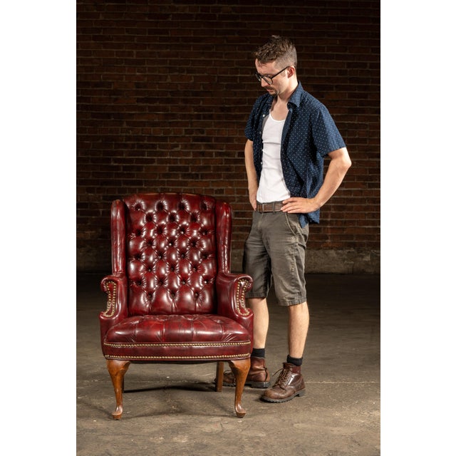 Handsome tufted leather armchair upholstered in deep oxblood leather, with button-tufting across the high back and seat....