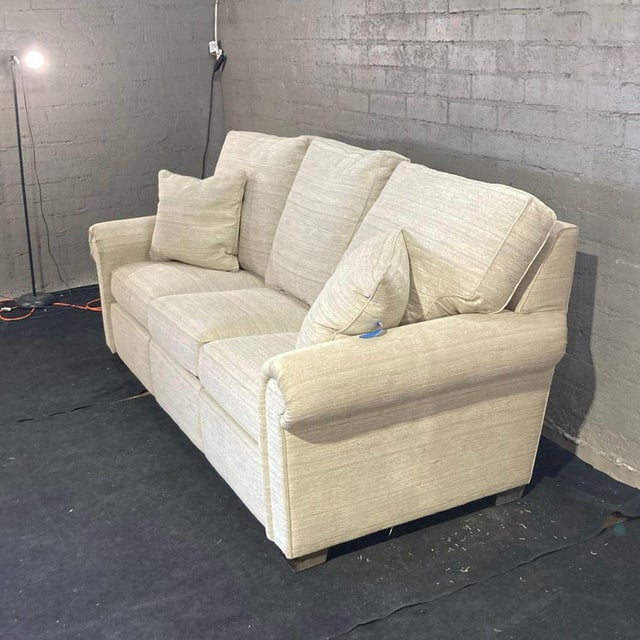 This Stickley 3-seat sofa features a soft light beige fabric and comes with two matching throw pillows. The sofa has...