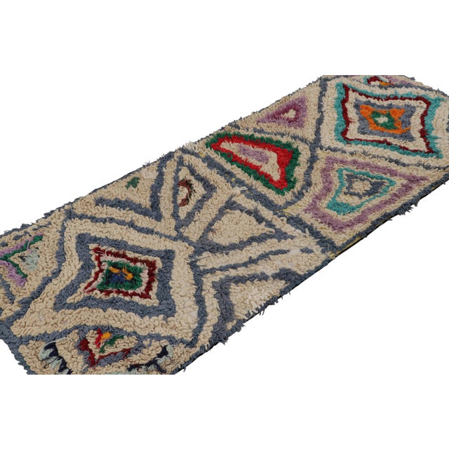 Hand-knotted in wool circa 1950-1960, this 3x7 vintage Moroccan runner rug with polychromatic diamond medallions, hails...