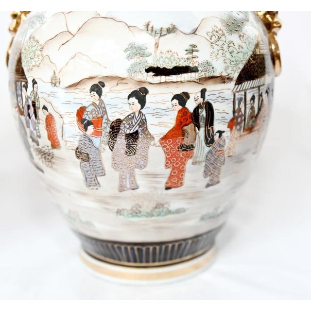 Decorative pair of Japanese Satsuma style vases with rounded bodies and flared rims Each features detailed figural scenes...