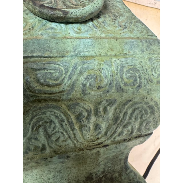 Vintage Chinese table lamp featuring a beautifully detailed bronze body with raised decorative motifs and sculptural side...