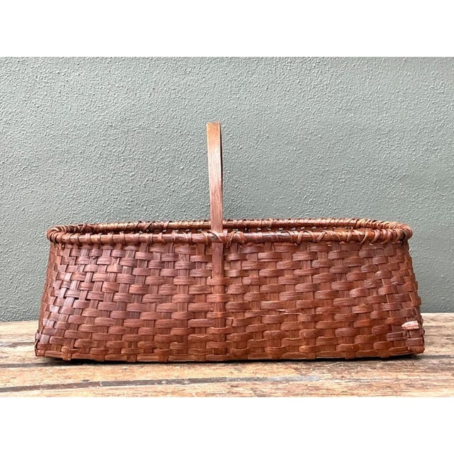This vintage woven rattan basket pairs a rectangular body with an arched handle, drawing on the spare, practical character...