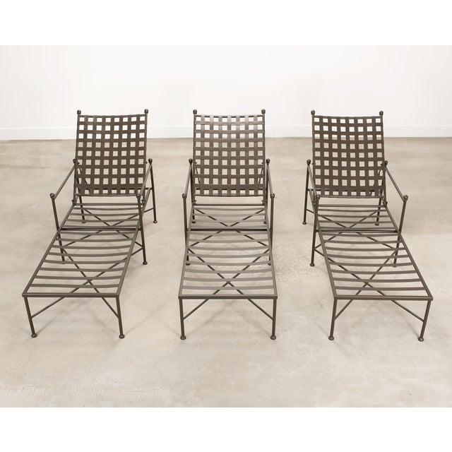A refined set of three matching wrought iron chaise lounges or longues crafted in the mid-century modern manner and style...