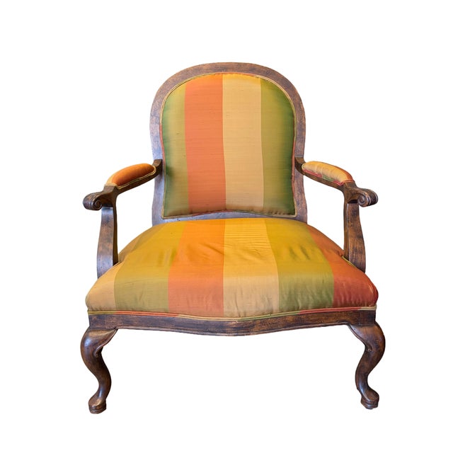 Pair of French Louis XV-style armchairs featuring carved wood frames with distressed, antiqued finishes, scrolled armrests...