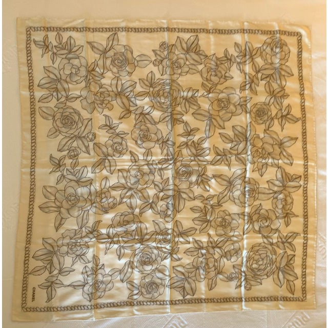 This elegant Chanel silk square scarf features an allover ivory and gray camellia floral print with delicate chain-stitch...