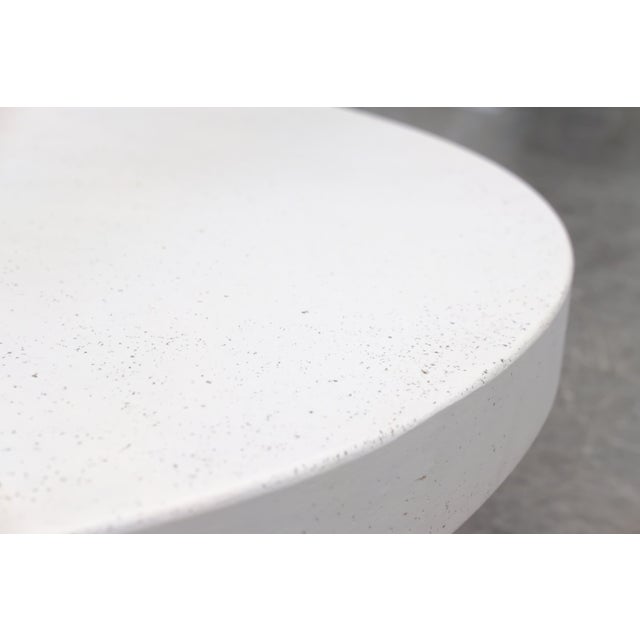 A large round coffee table with a substantial burl wood base, showing rich, swirling grain and a lustrous finish, paired...