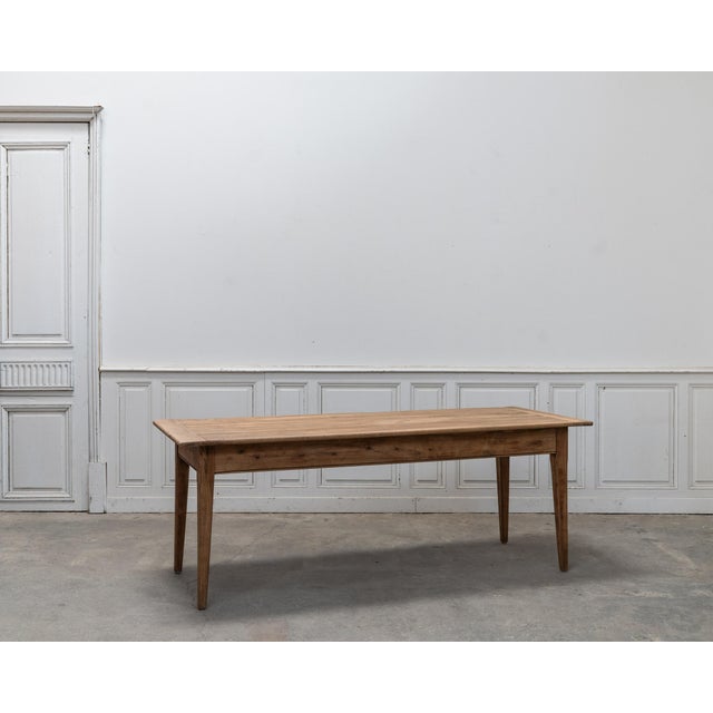 This solid walnut farmhouse table, dating from the 1900s, captivates with its clean lines, beautiful proportions, and the...