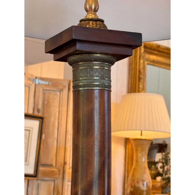 A handsome column lamp in mahogany with applied bronze mounts throughout. The square base has a bronze acanthus-leaf...