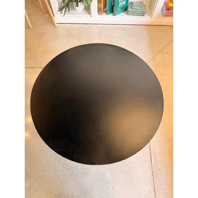 Industrial-inspired adjustable dining table featuring a sleek matte black round iron tabletop paired with a bold cast iron...
