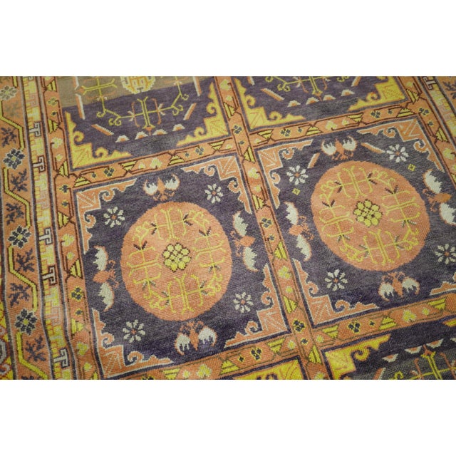 One of a kind Khotan rug with a repetitive all-over design on an eggplant ground highlighted by peach and yellow outlined...