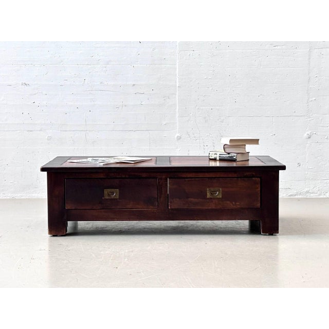 A characterful coffee table crafted from solid wood in a dark brown finish. The heavy, low construction, wide frame, and...