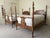 A pair of twin sized four poster beds featuring carved wooden headboards with scrollwork and urn finials, low footboards...
