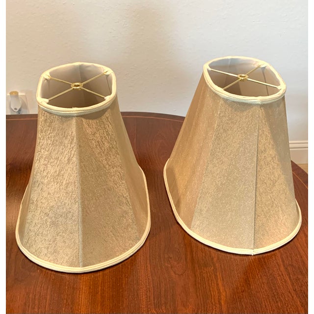 Offering a pair of silk lampshades featuring gold threads. Trim and inside fabric are off white.