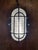 Vintage industrial bulkhead light featuring a robust cast metal housing, protective steel cage and original ribbed...