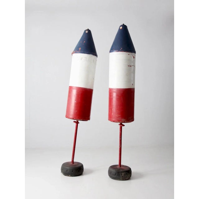 Pair of large vintage nautical buoys on stands. Impressive oversized torpedo-shaped buoys featuring a classic red, white,...