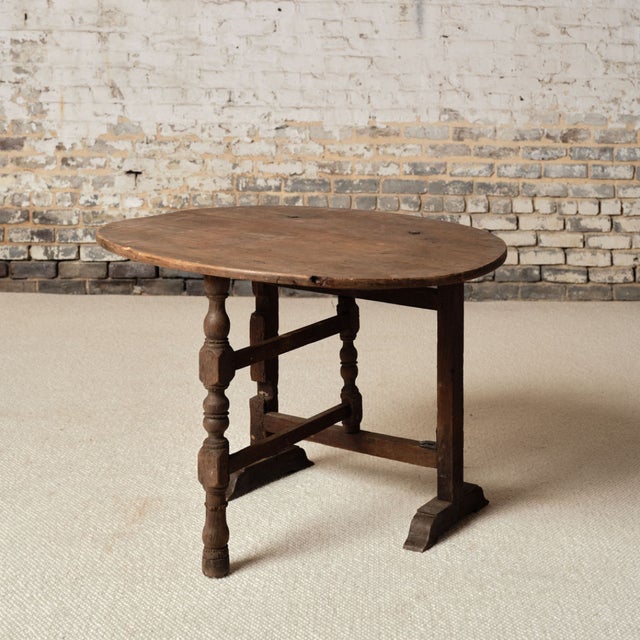 This 19th Century French Oak Table de Vin features a beautifully aged circular top with a warm, timeworn patina and subtle...