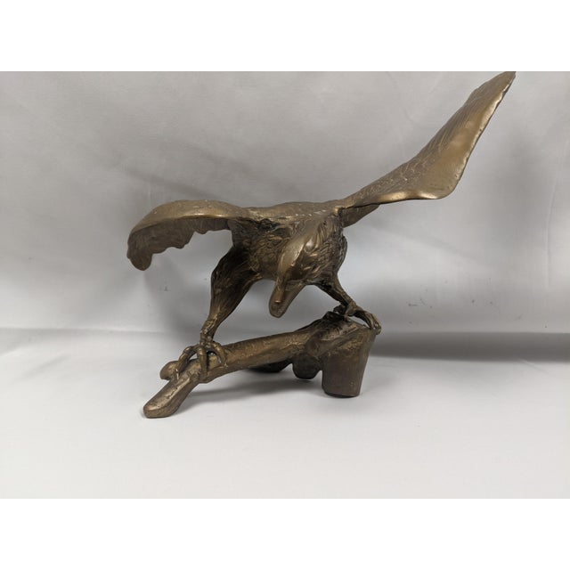 An impressive vintage solid brass eagle sculpture depicting a majestic bird of prey poised on a naturalistic tree branch...
