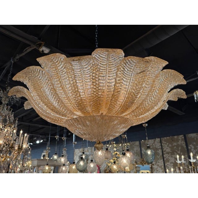 The Gold "Granola" Murano Glass Flush Mount Chandelier is a luxurious and elegant lighting fixture that adds a touch of...