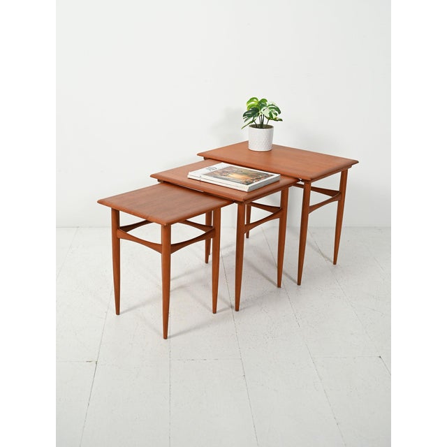 Set of three Scandinavian teak nesting tables, 1950s–60s, featuring slender turned legs and tops with delicately chamfered...