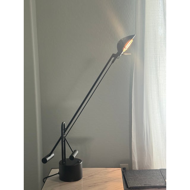 This is a 1990s post modern desk lamp featuring a sleek matte black finish. It can be adjusted for flexible lighting and...