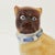 This exquisite, antique porcelain Pug dog is seated with open front legs. He is wearing a bright blue, ribbon collar...