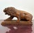 This hand-carved wooden sculpture depicts a lion in a crouched, powerful stance, with one paw extended forward and its...
