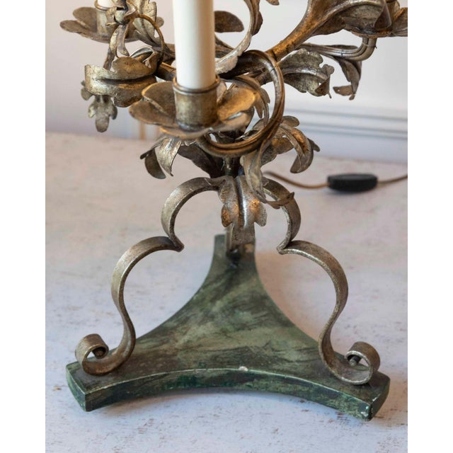 Elegant pair of 20th century Italian wrought iron three-light candelabra table lamps featuring a warm mecca silver-leaf...