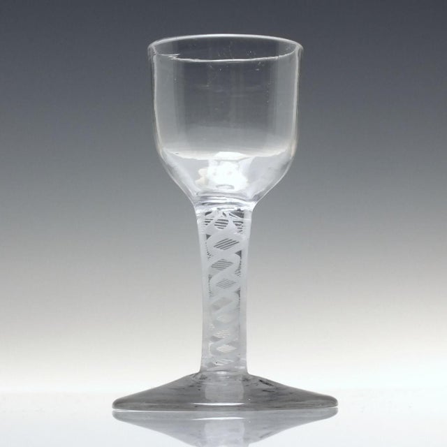 An antique 18th century opaque twist dram glass with a round funnel bowl. Rests upon a double series opaque twist stem...