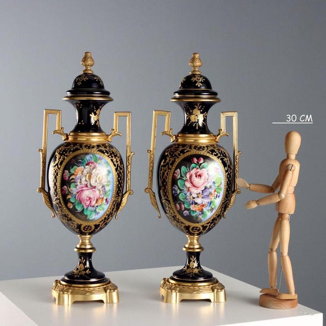 A pair of blue porcelain and gilt bronze vases. Decorated in pure gold with plant motifs and a floral arrangement on the...