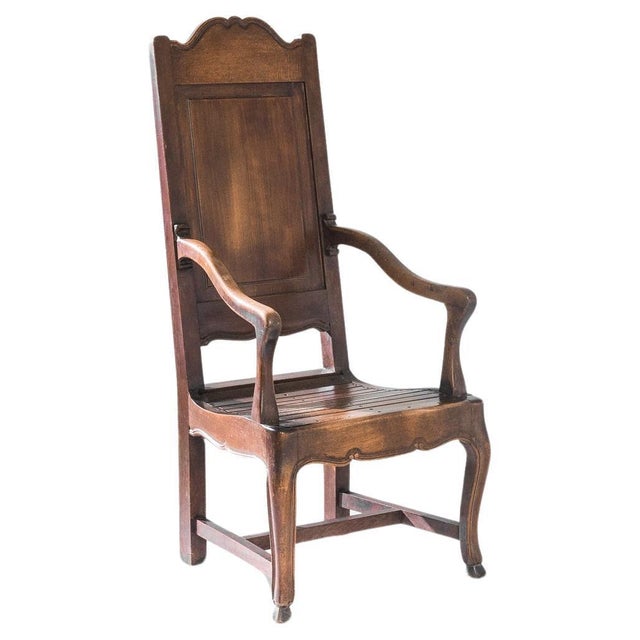 A wooden armchair created in early 20th century Belgium. High-backed and dignified, this sumptuous armchair radiates an...