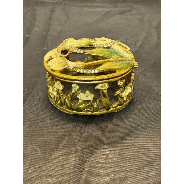 The product is a vintage round brass trinket box with white lily enamel design in the Art Nouveau style, measuring 5.5...