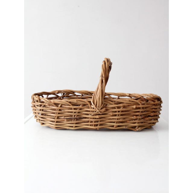 A beautifully weathered vintage gathering basket with an elongated oval form, high arched handle, and wonderfully...