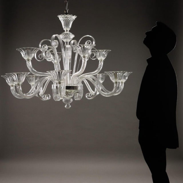 Venetian chandelier in transparent blown glass, twelve lights arranged on a double stage. Wavy arms alternating with...