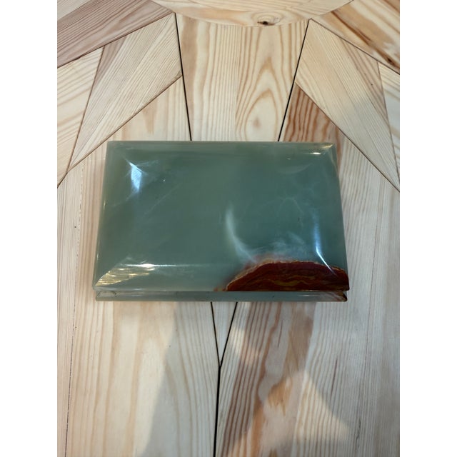 An elegant footed box carved from natural banded stone (likely onyx or marble) in soft celadon/sage green with dramatic...