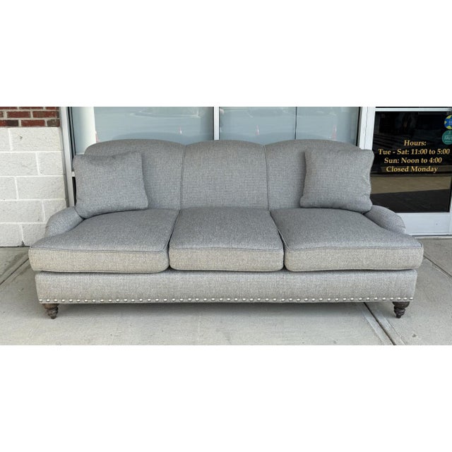 This Arhaus upholstered three-seat sofa features a refined gray-blue woven fabric, classic rolled arms, and a gently...
