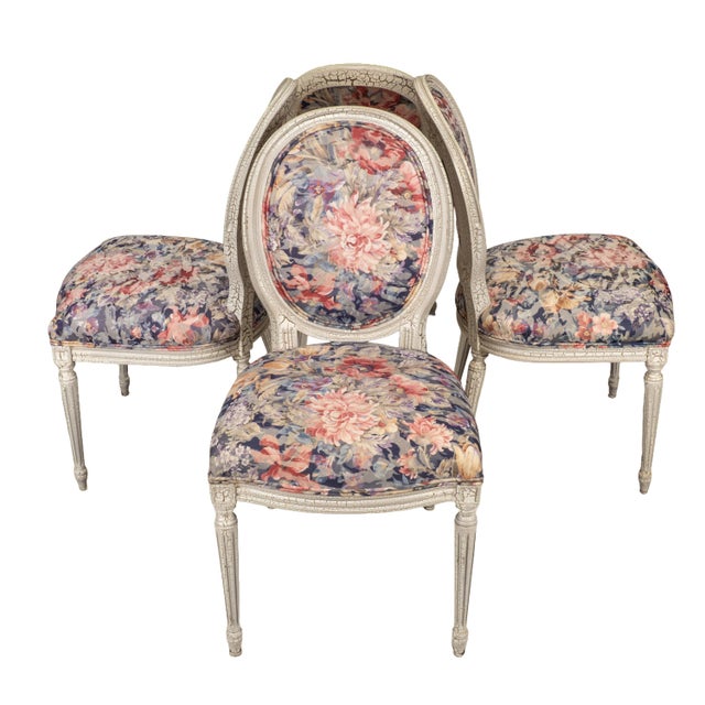 Set of four French style dining chairs with a distressed painted finish and vibrant floral upholstery. The frames feature...