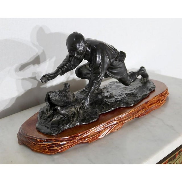 Charming bronze with dark brown patina, representing a peasant trying to capture a bird with the help of his hat. The man...