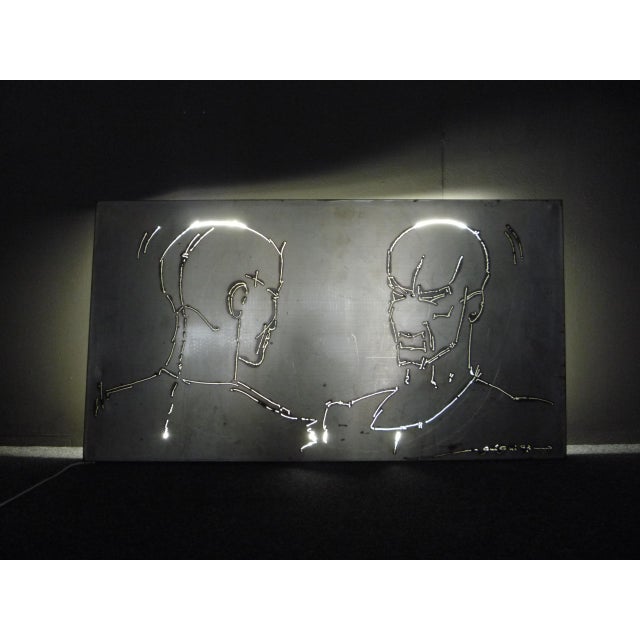 Brutalist metal wall object with lighting. Designed and manufactured by Gui Gui. Signed. Motif 2 men and decorative....