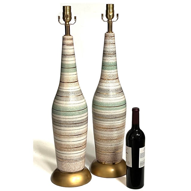 each tall lamp with long neck above a tapering body all in a crackle glaze finish with celadon, gray and buff stripes...