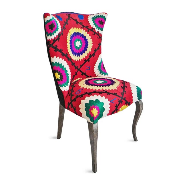 Striking accent chair upholstered with vintage colorful Suzani fabric. Traditional curved front legs and wingback style....