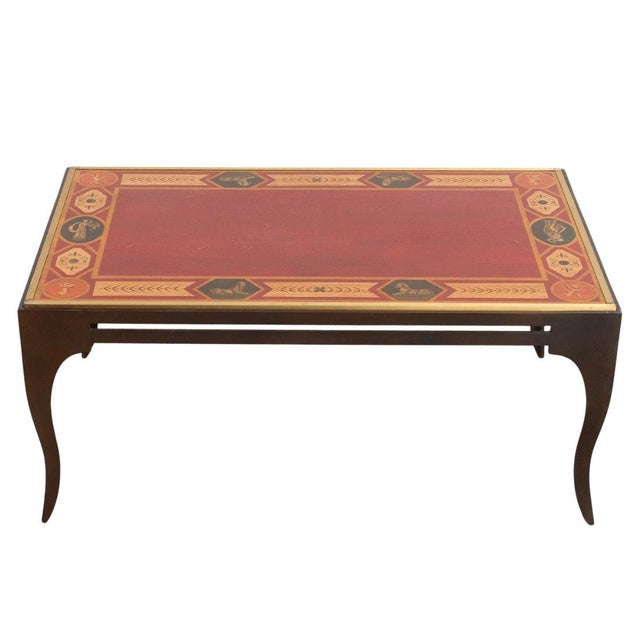 A vintage metal coffee table with a painted top in a classical Greco Roman motif with figures and medallions. The table...