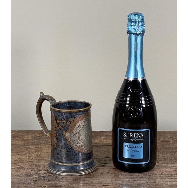 This silverplate tankard is formed in a straight sided cylindrical shape with a flared foot, a curved handle, and an...