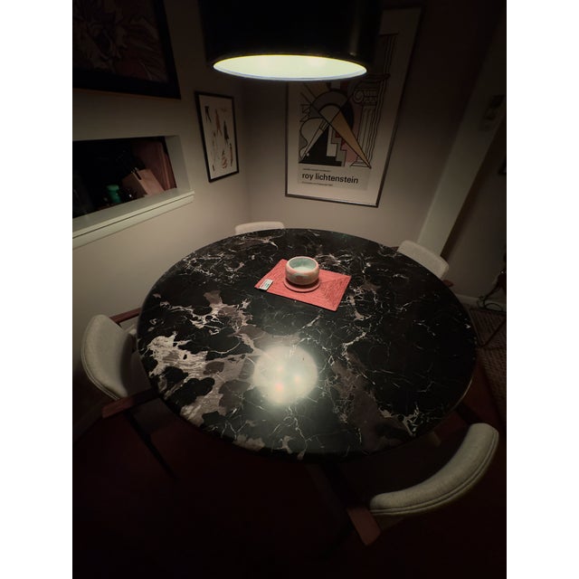 A striking round dining table with a solid slab of black Italian marble on top and sculptural oak pedestal base. The...