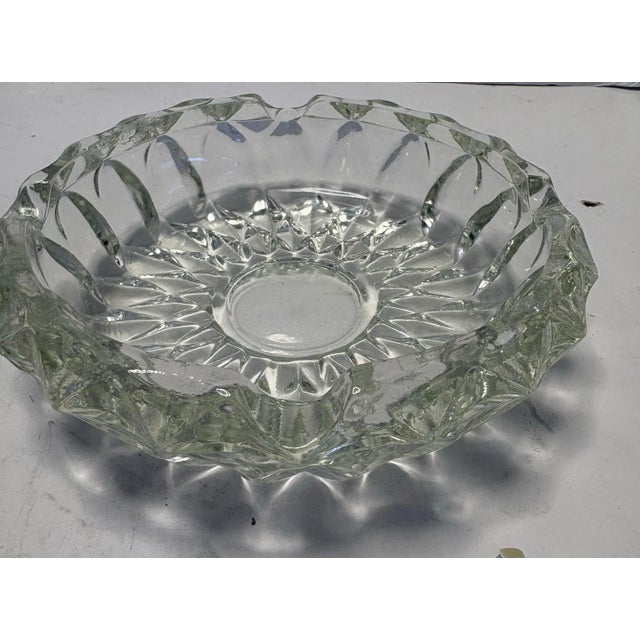 crafted in heavy pressed glass, featuring a crisp starburst motif that radiates from the base and a faceted, scalloped rim...