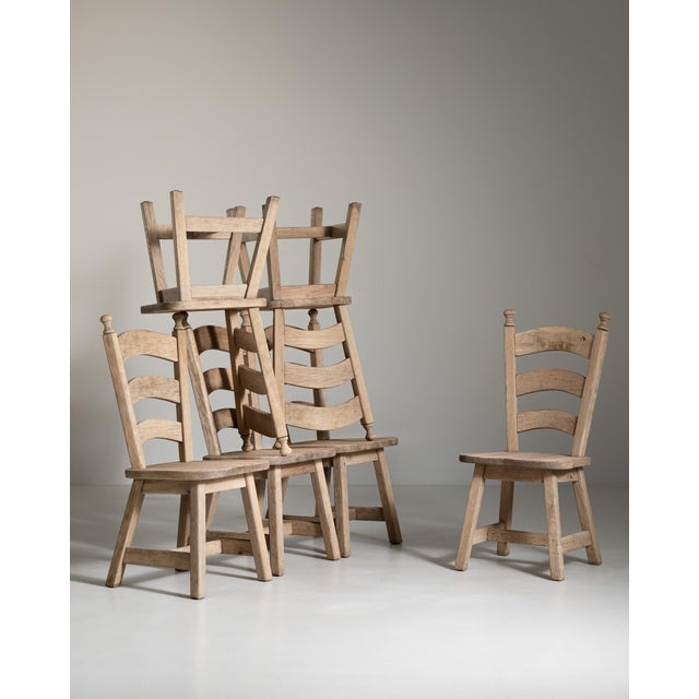 A distinguished set of six French oak dining chairs, dating to circa 1970, reflects the enduring elegance of mid-century...