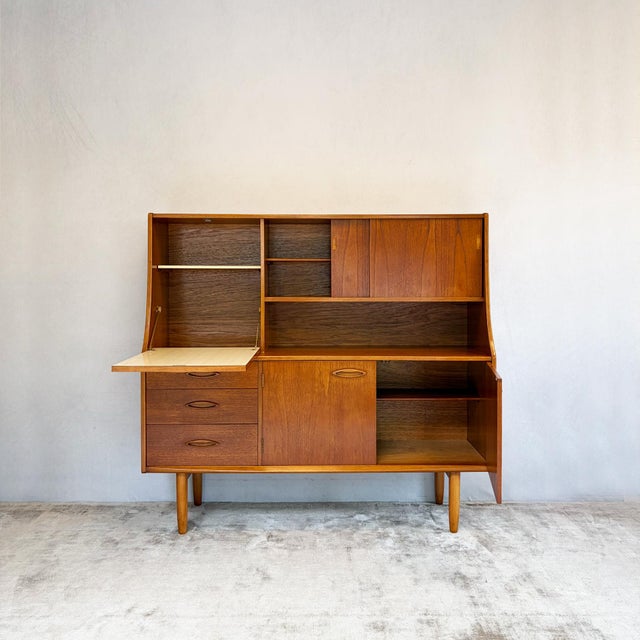 A teak highboard by Jentique with a fitted drinks section. Teak veneer construction with dovetailed drawer boxes, recessed...