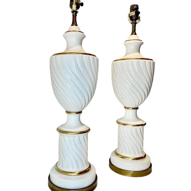 Matching Hollywood‑Regency lamps from Paul Hanson feature ribbed white ceramic urns circled with gilt rings and mounted on...