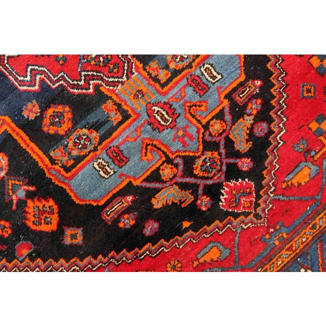 Handmade vintage Middle Eastern rug in red and blue shades. The rug has been made in wool in the middle of 20th century....